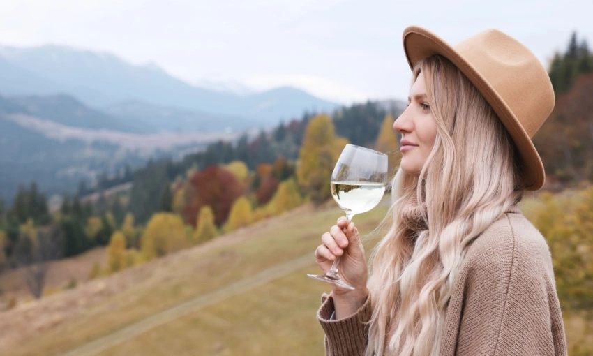 Donna che degusta vino bianco in montagna