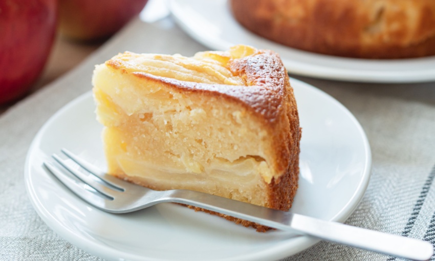 Fetta di torta di mele su un piatto bianco con accanto una forchettina da dolce