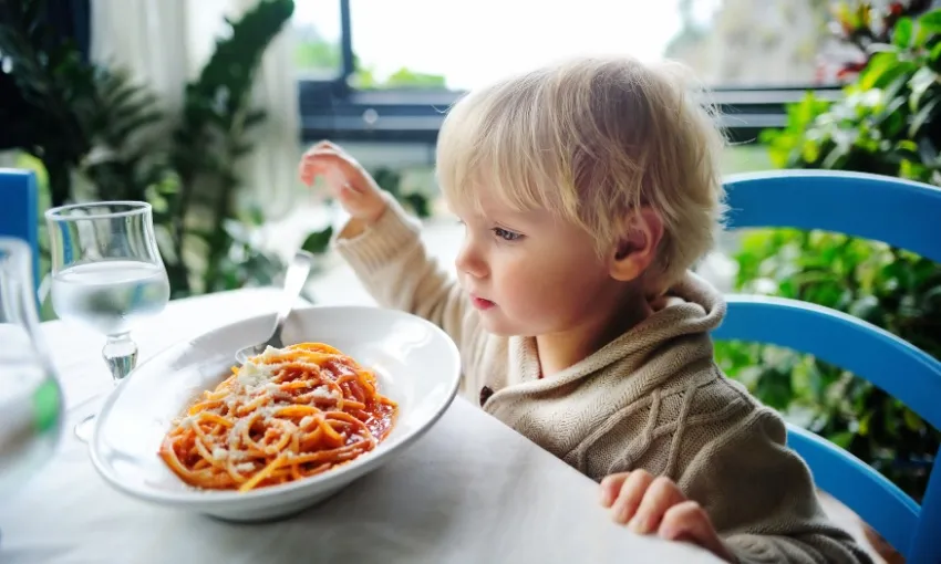 Bambino che mangia un piatto di spaghetti al pomodoro