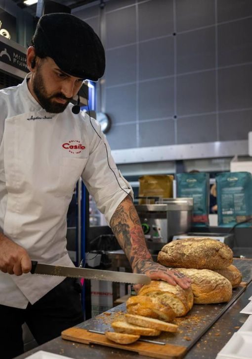 Agatino Arena che taglia pane su un tagliere durante uno showcooking