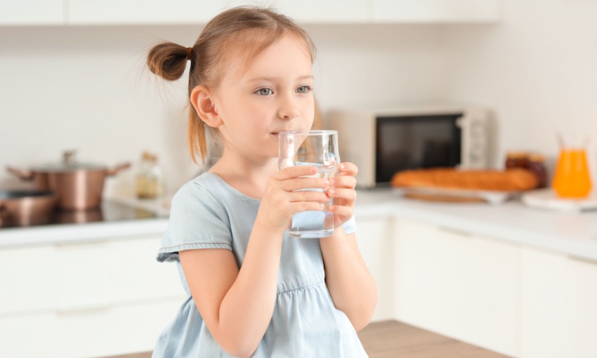 Bambina che beve un bicchiere d'acqua