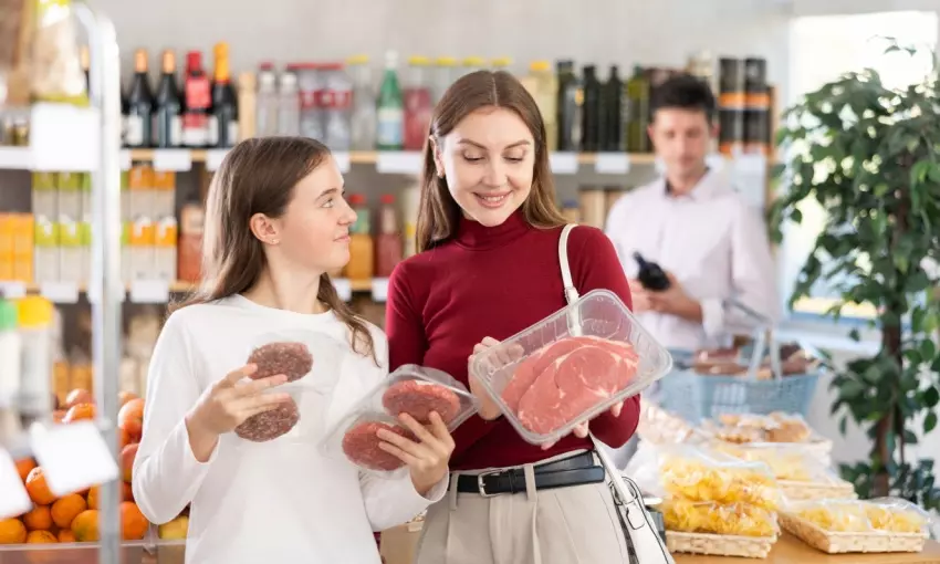 Mamma e figlia al supermercato che leggono etichette sulle vaschette della carne